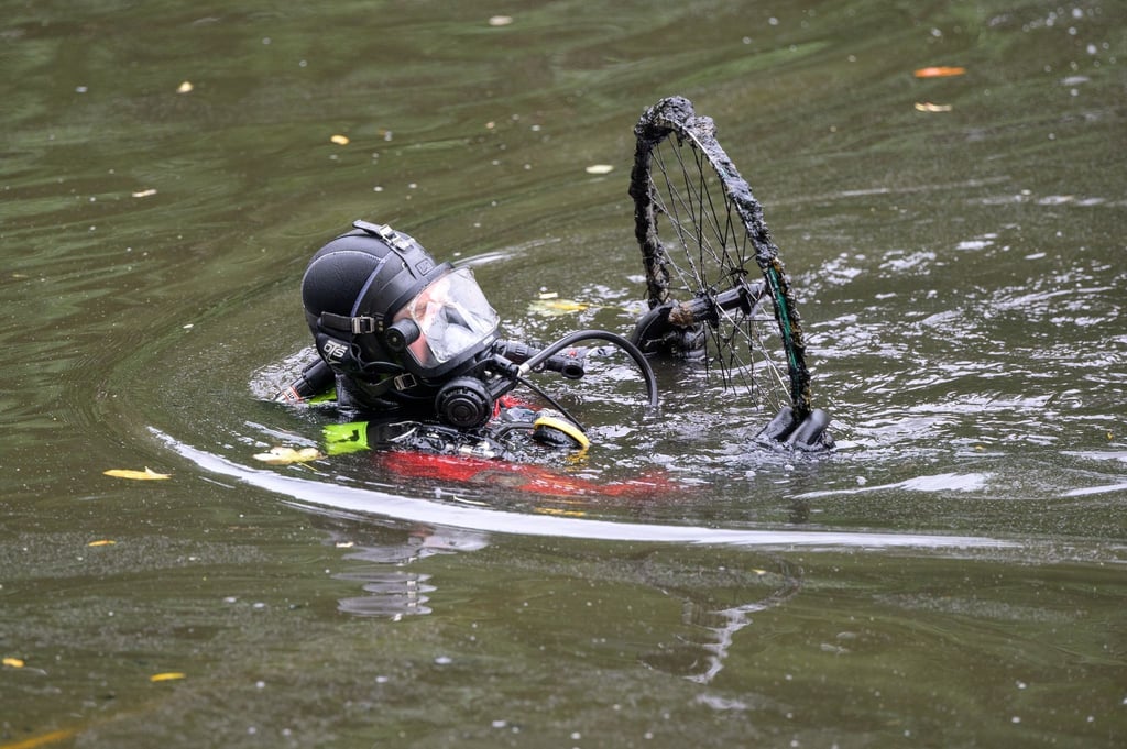 Ein Taucher der Feuerwehr holt einen alten Fahrradreifen aus dem Isebekkanal.