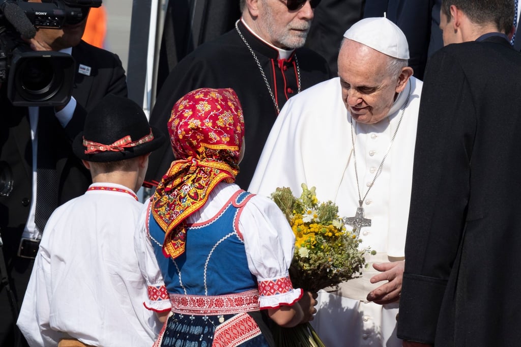 Papst Franziskus wird von zwei Kindern in traditioneller Kleidung am Flughafen im slowakischen Bratislava empfangen.