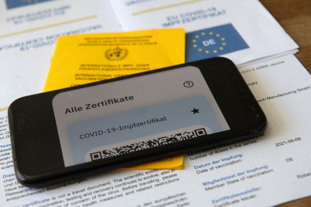 Ein Impfpass und ein Smartphone, auf dem die App CovPass läuft.
