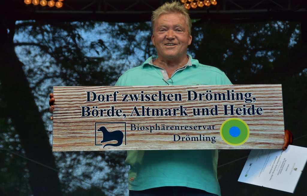 Klüdens Ortsteilbeauftragter Wilfried Leberecht nimmt den Glückwunsch zum Titel und das Schild entgegen.