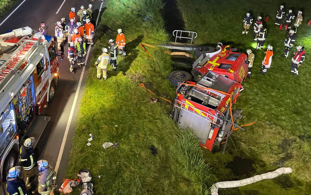 Feuerwehrleute stehen um ein verunfalltes Einsatzfahrzeug auf der B212 bei Brake (Unterweser).