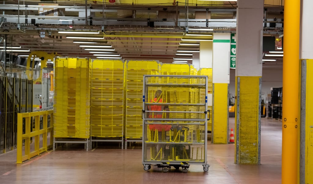 Ein Mitarbeiter fährt bei Amazon einen leeren Palettenwagen in ein Lager.