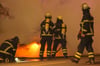 Symbolbild: Feuerwehrleute löschen ein brennendes Fahrzeug.