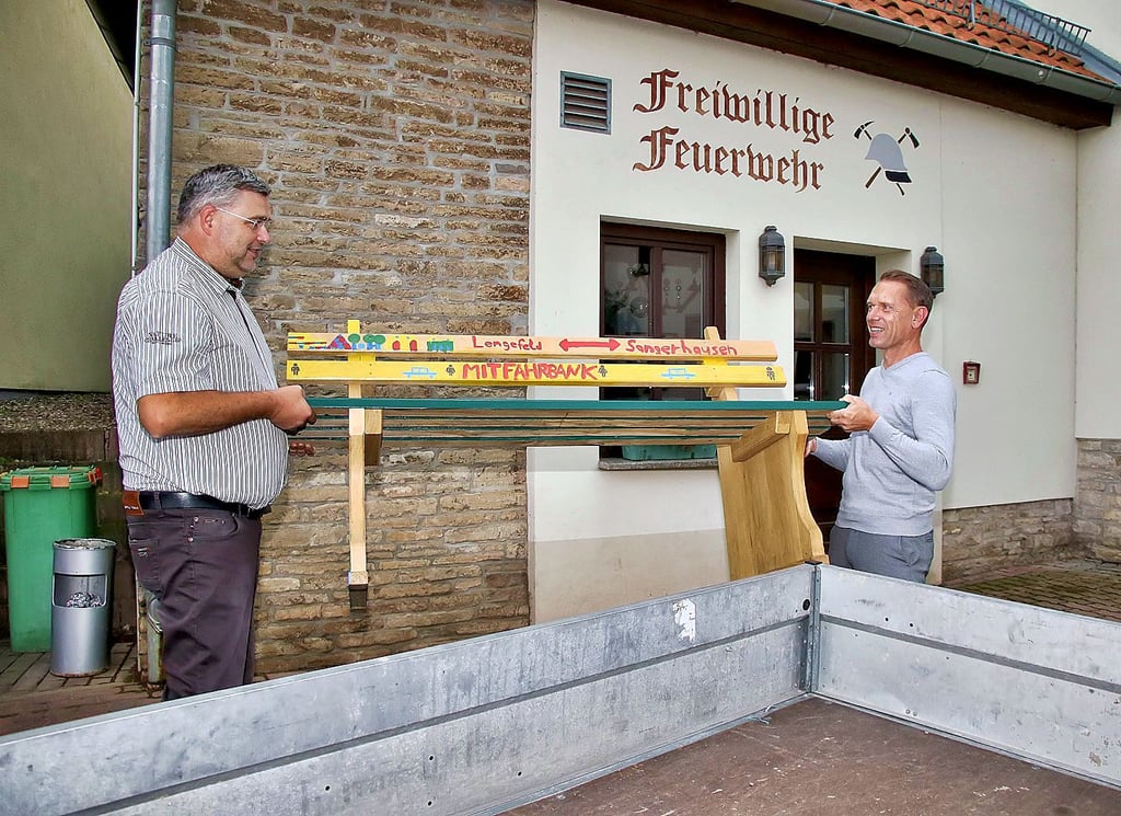 Frank Schmiedl (links) und Ortsbürgermeister Daniel Maertens stellen die Bank an der Feuerwehr in Lengefeld auf.