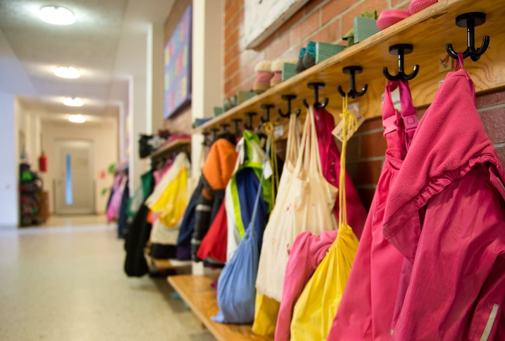 Jacken und Turnbeutel sind in einer Kindertagesstätte an einer Garderobe zu sehen.