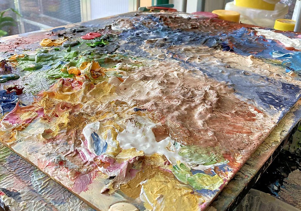 Wie Gebirgszüge erstrecken sich die getrockneten Farben auf einer hölzernen Oberfläche im Atelier der Malerin, die in Merseburg Grafikdesign unterrichtet.