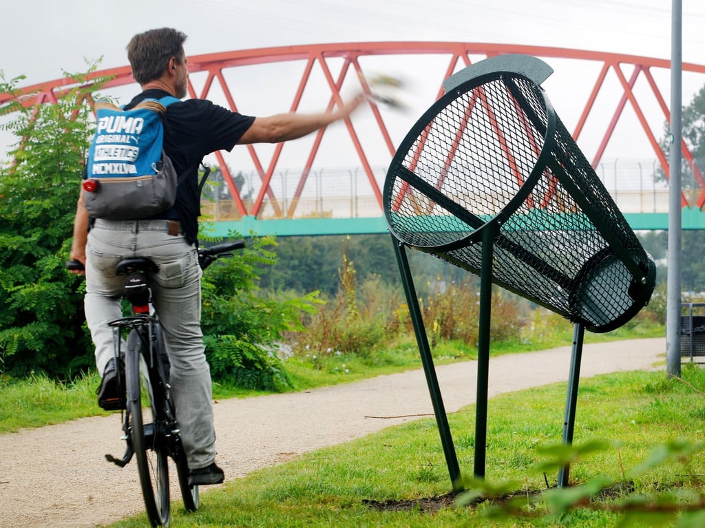 Ein Fahrradfahrer wirft am Rhein-Herne-Kanal seinen Müll im Vorbeifahren in einen der neuen Wurfmülleimer.