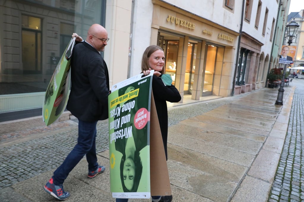 Wolfgang Wetzel, (l) Spitzenkandidat der Grünen und Christin Furtenbacher, Landesvorstandssprecherin der Grünen in Sachsen, laufen mit Wahlplakaten durch die Innenstadt von Zwickau.