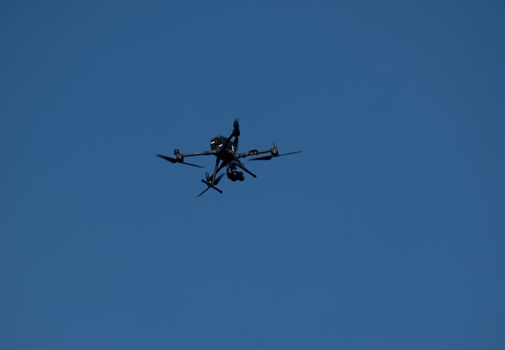 Eine Drohne der Polizei fliegt über eine Parkanlage.