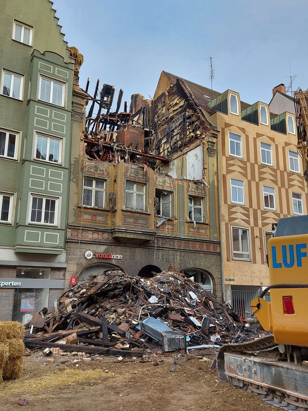 Nach einem verheerenden Brand liegen Trümmerteile vor einem denkmalgeschützten Haus.