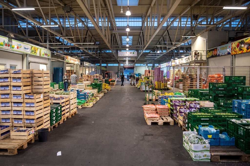 Kisten mit Obst und Gemüse stehen in einer Halle des Großmarktes.