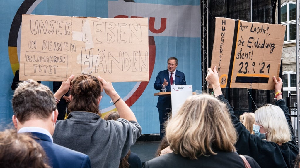 Demonstrierende halten bei einem Wahlkampfauftritt von Armin Laschet Plakate hoch.