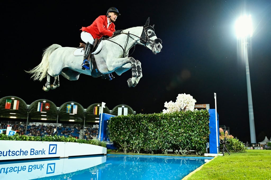 Springreiter Christian Ahlmann auf Pferd Clintrexo überspringt ein Wasserhindernis.