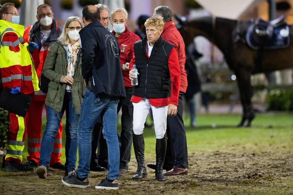 Marcus Ehning (2.v.r) steht nach seinem Sturz neben Sanitätern und Ärzten und Bundestrainer Otto Becker (r).