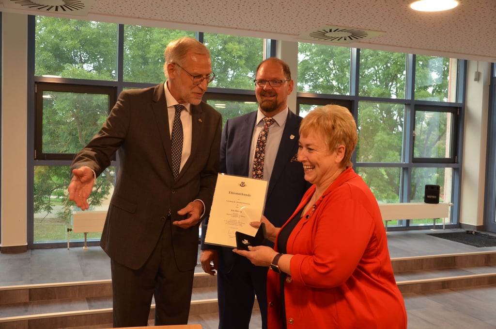 Iris Herzig erhielt vom Landkreistag-Geschäftsführer Heinz-Lothar Theel (l.) die Silberne Ehrennadel und war sichtlich überrascht. Landrat Martin Stichnoth dankte ihr im Namen der Verwaltung.
