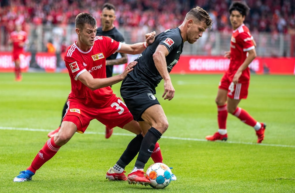 Augsburgs Florian Niederlechner (r) schirmt den Ball gegen den Unioner Robin Knoche ab.