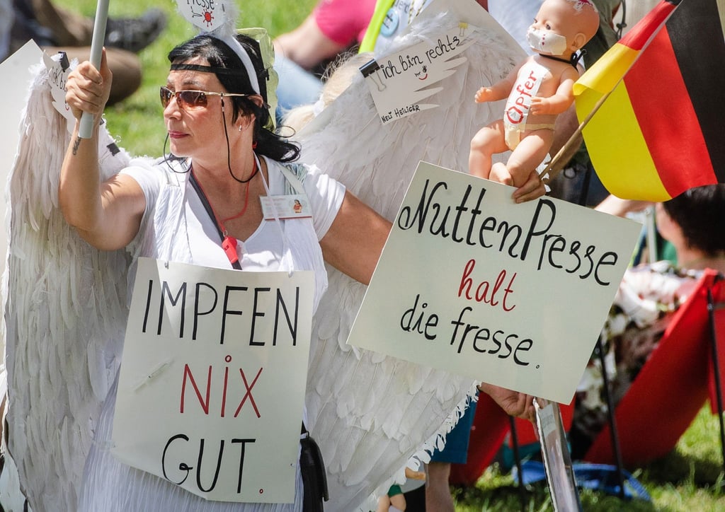 Eine Demonstrantin mit Schildern nimmt an einer Demonstration der Initiative „Querdenken“ teil.