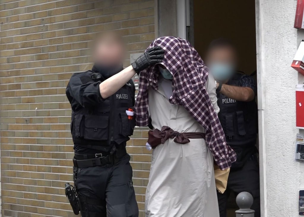 Ein Mann wird im Zusammenhang mit dem mutmaßlich geplanten Anschlag von Polizisten abgeführt.