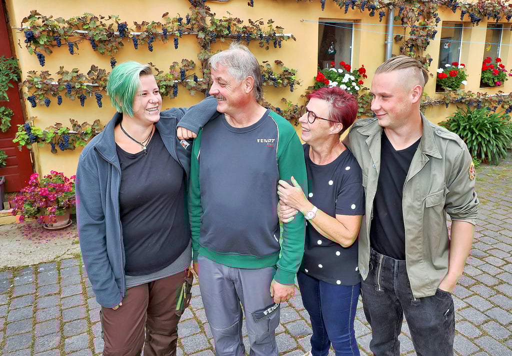 Lisa, Jürgen, Marlit und Felix Tambach (v.l.) auf dem Dreiseitenhof der Familie in Winkel. Den Weinstock mit den prächtigen Reben haben die Eltern 1995 gepflanzt. Sie hatten ihn von einem Weinbauern zur Hochzeit bekommen. Im Hofladen gibt es die Produkte der Tambachs und anderer Direktvermarkter.