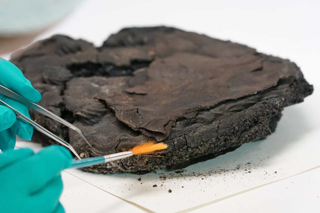 Eine Restauratorin reinigt mit Pinsel und Pinzette eine 79 Jahre alte Nusstorte in der Werkstatt der Lübecker Stadtarchäologie.