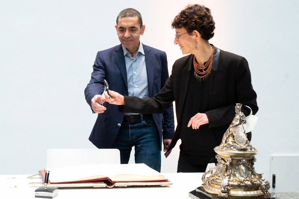 Ugur Sahin (l) und Özlem Türeci reichen sich den Stift weiter.