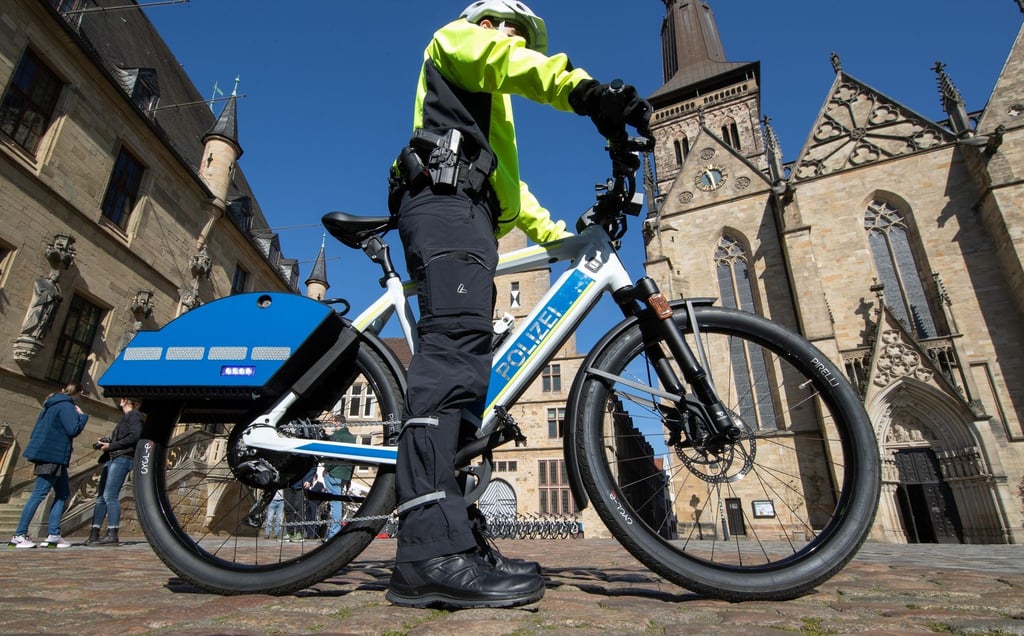 Ein Polizist steht auf einem S-Pedelec mit Blaulicht und Martinshorn.