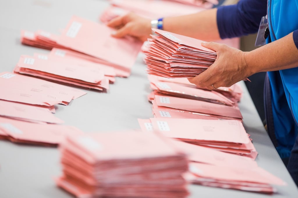 Wahlhelfer sortieren die roten Wahlbriefe mit den abgegebenen Stimmen.