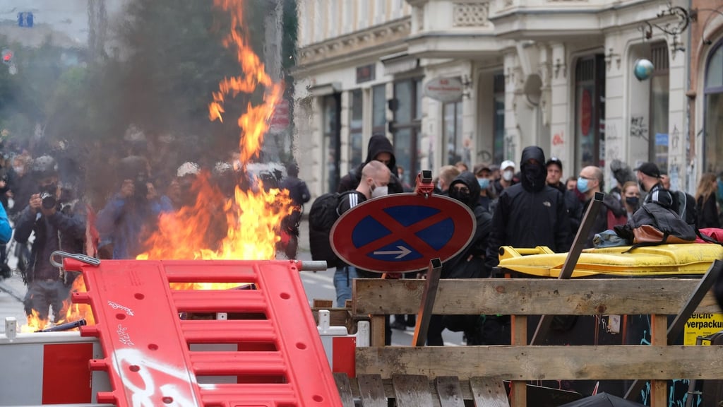 Maskierte Demo-Teilnehmer stehen hinter einer Barrikade.