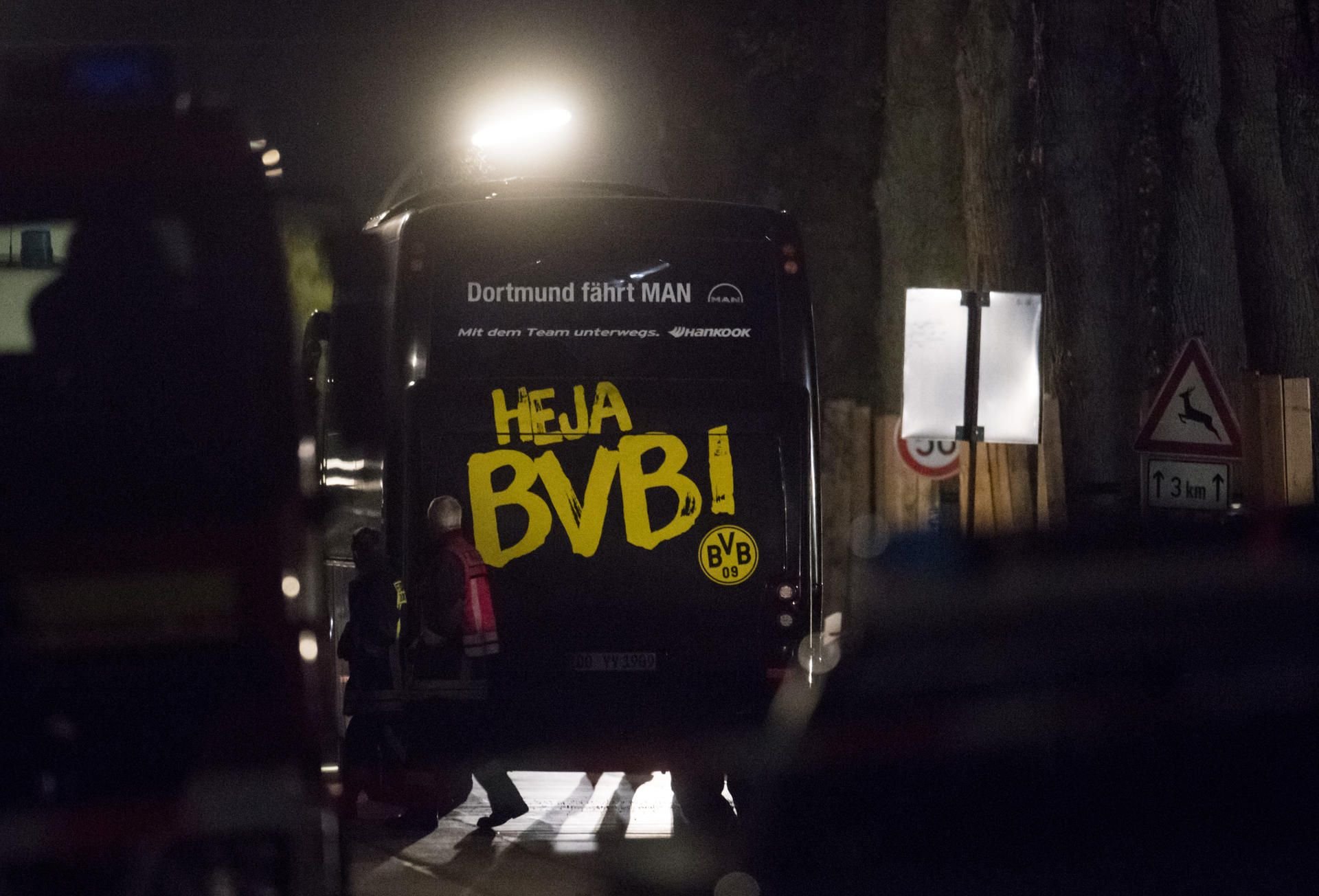 Einsatzkräfte der Feuerwehr gehen am 11.04.2017 in Dortmund (Nordrhein-Westfalen) am Mannschaftsbus der Fußballmannschaft von Borussia Dortmund vorbei, in dessen Nähe es am Abend drei Explosionen gegeben hatte.