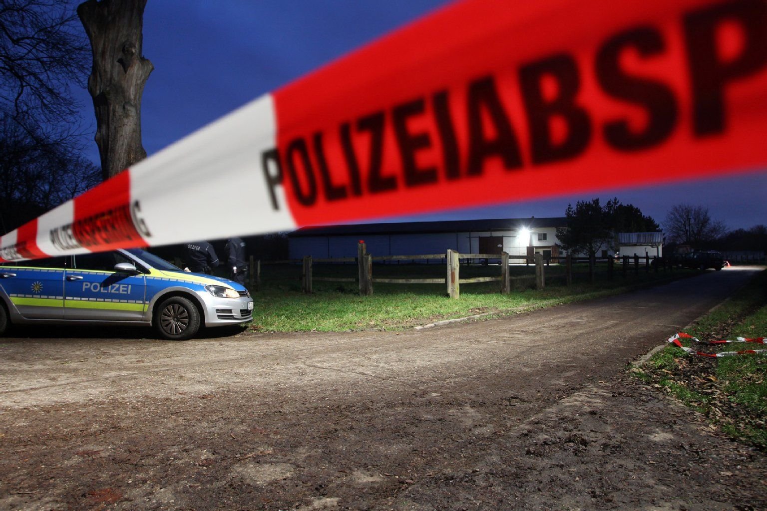 Ein Fahrzeug der Polizei steht am 03.12.2015 in Leipzig (Sachsen) hinter einer Polizeiabsperrung vor einem Reiterhof im Stadtteil Knauthain.