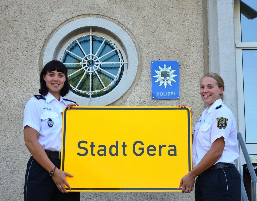 Anja Koppsieker und Carolin Neugebauer mit dem Ortseingangsschild von Gera