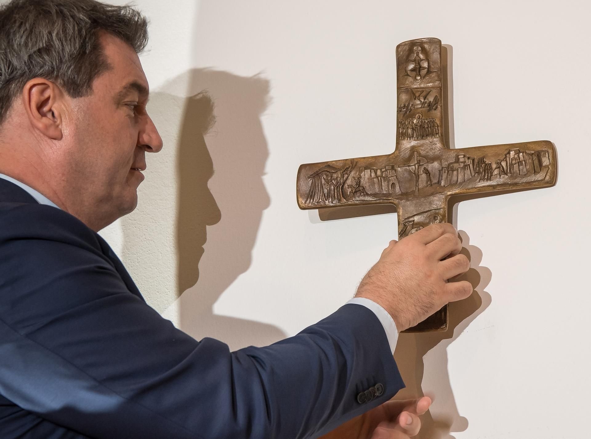 Markus Söder hängt ein Kreuz im Eingangsbereich der bayerischen Staatskanzlei auf.
