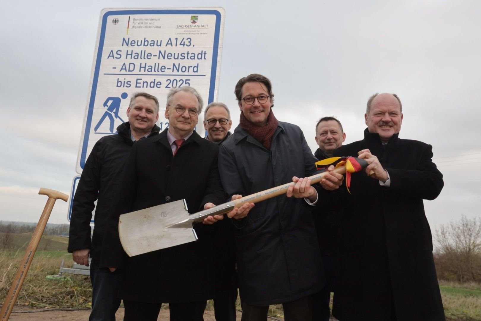Unter dem Bundesverkehrsminister Andreas Scheuer (Mitte), Sachsen-Anhalts Ministerpräsident Reiner Haseloff (mittig links), Sachsen-Anhalts Verkehrsminister Thomas Webe (rechts), Landesabgeordneten Frank Bommersbach (hinten rechts) und DESGES-Geschäftsführer Dirk Brandenburger wird der Spatenstich für das letzte Teilstück der A143 gesetzt.