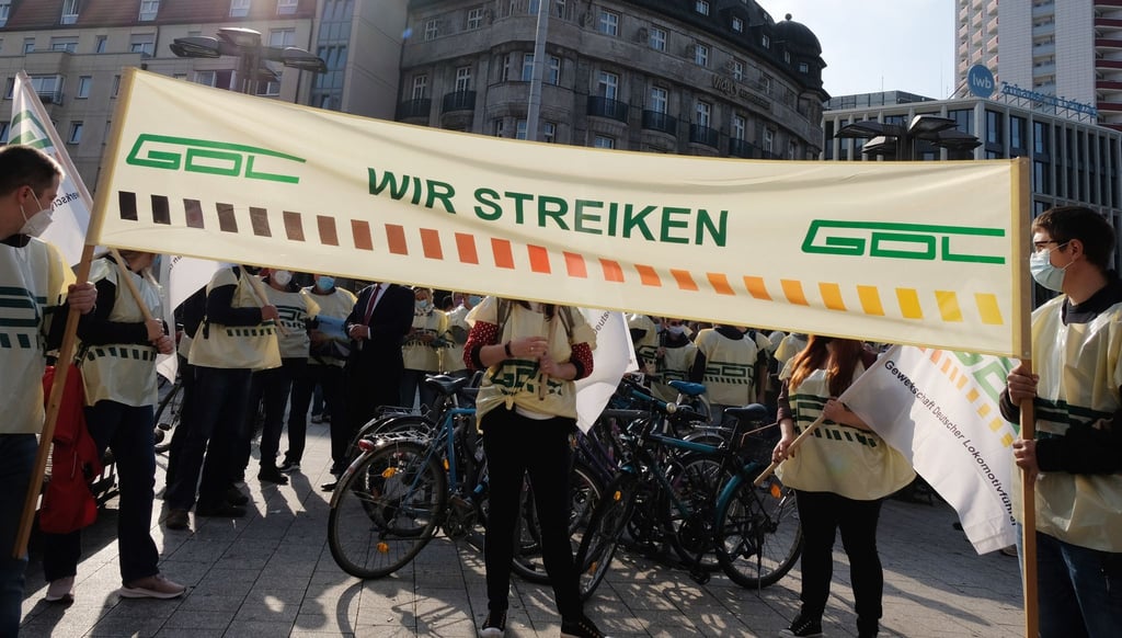 Teilnehmer einer Kundgebung der GDL stehen mit einem Transparent vor dem Leipziger Hauptbahnhof.