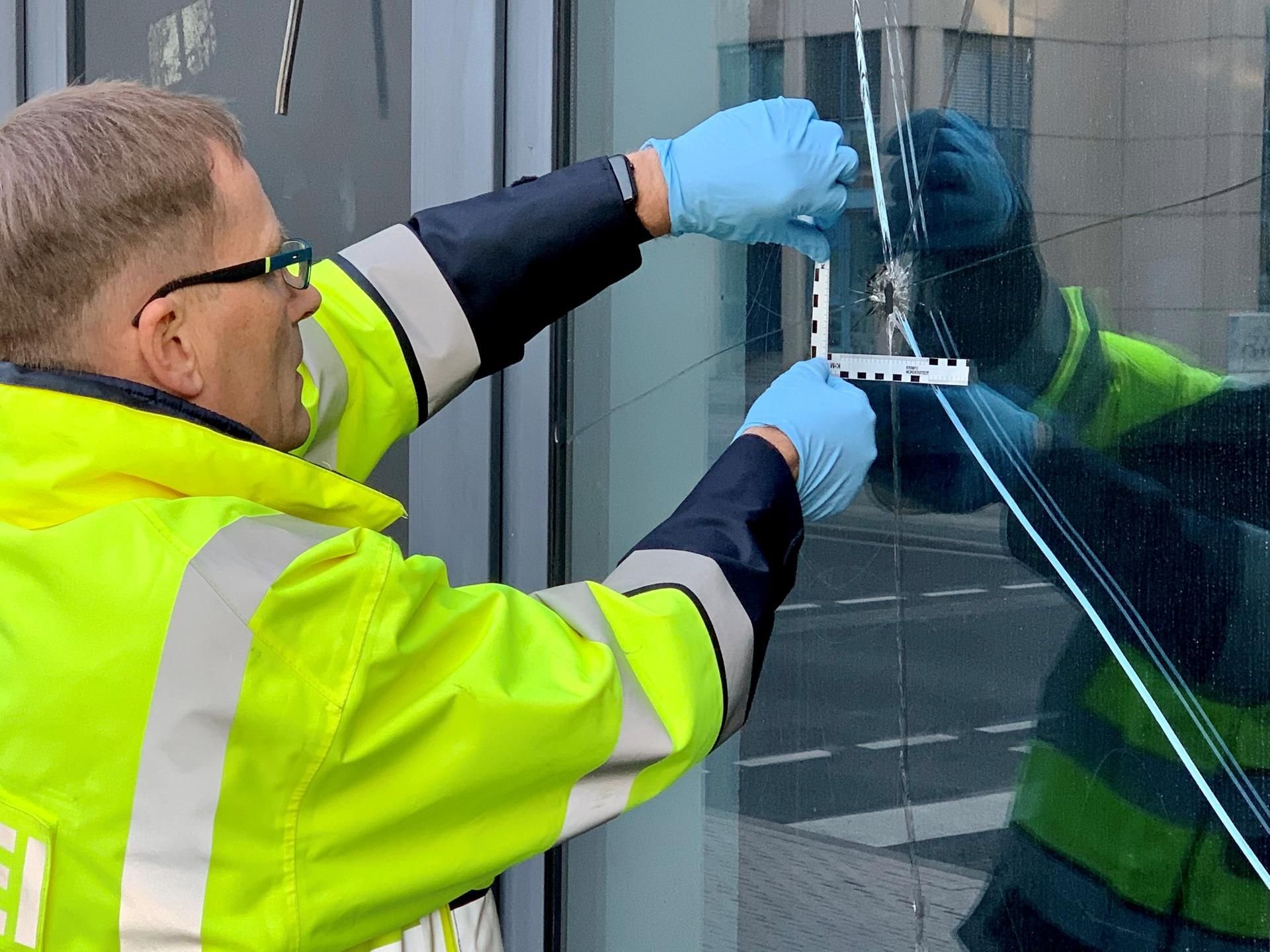 Ein Kriminaltechniker untersucht am Justizzentrum die Löcher im Sicherheitsglas des Gebäudes.