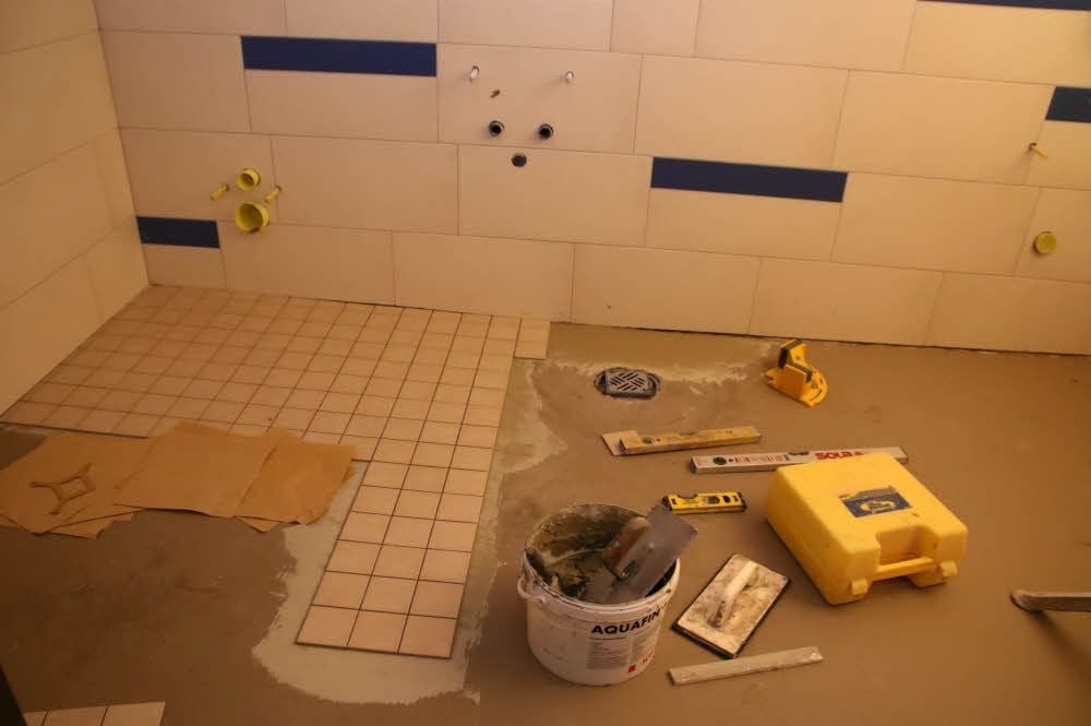 Die Fliesen im Sanitärtrakt werden verlegt.