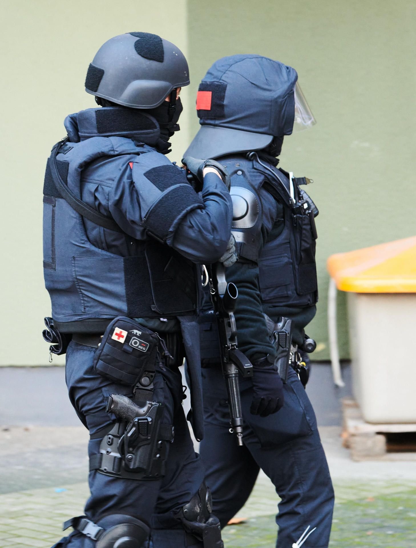 Bewaffnete Polizisten gehen während des Einsatzes in Berlin zu einem Hauseingang.