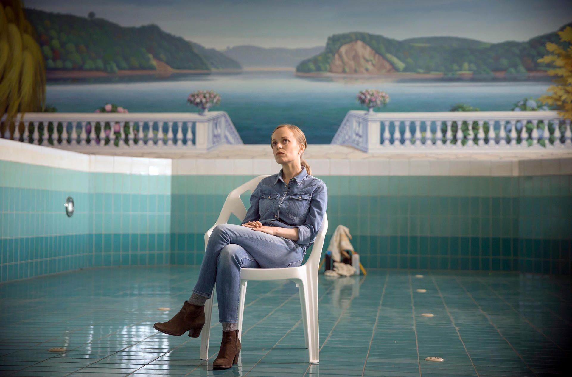 Nadeshda Krusenstern (Friederike Kempter) sitzt in einer Filmszene des Tatorts „Das Team“ im Schwimmbecken eines leerstehenden Hotels und wird von Kollegen befragt.