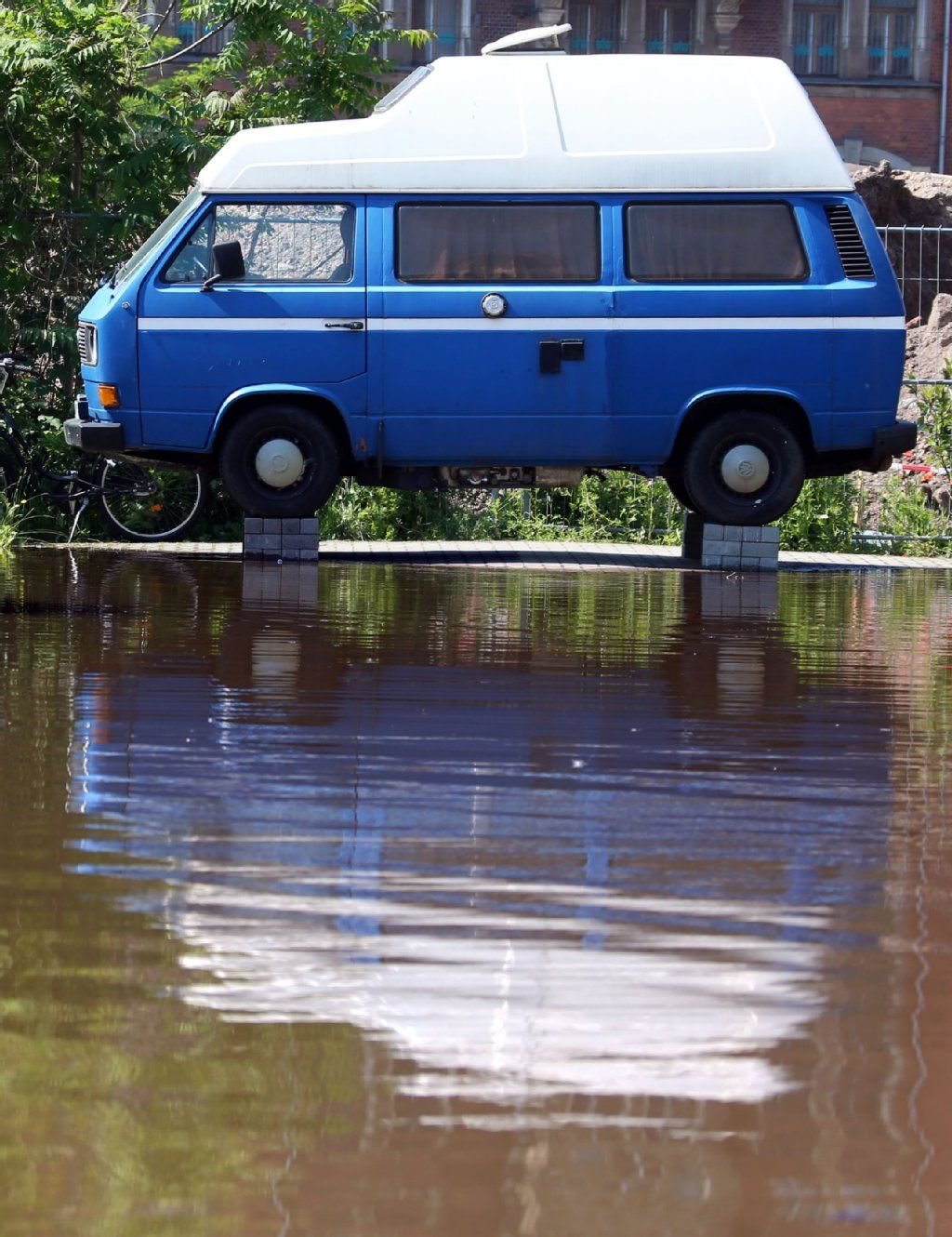 Ein VW-Bus steht in Magdeburg auf einem Sockel aus Steinen. Die Hochwassersituation an der Elbe spitzt sich weiter zu.