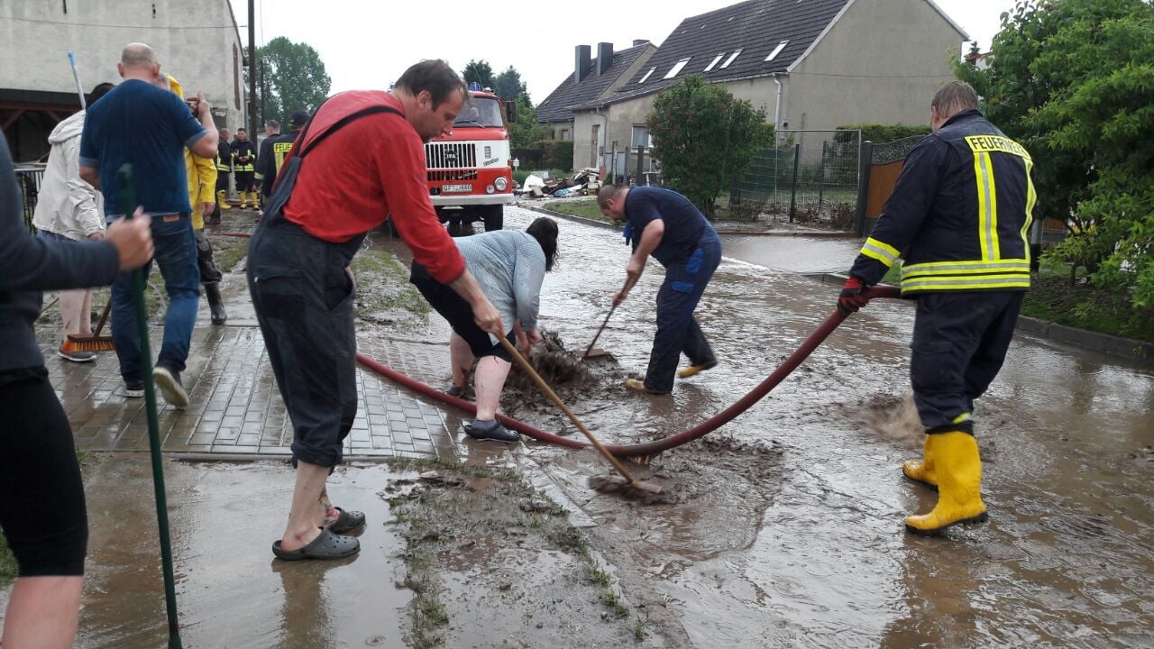 In Barnstädt läuft das Wasser kommt vom Feld in den Ort. Helfer versuchen auf der Oechlitzer Straße es abfließen zu lassen.