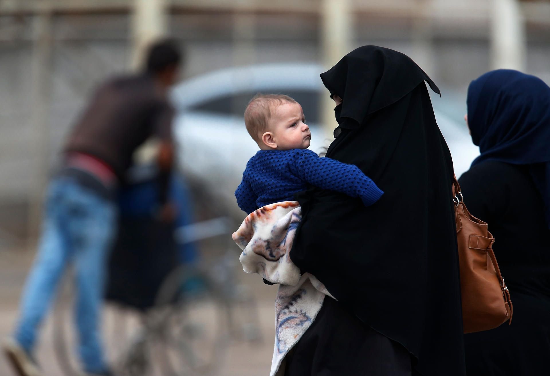 Ein Syrerin überquert mit einem Baby auf dem Arm die Grenze zur Türkei. (Symbolbild)