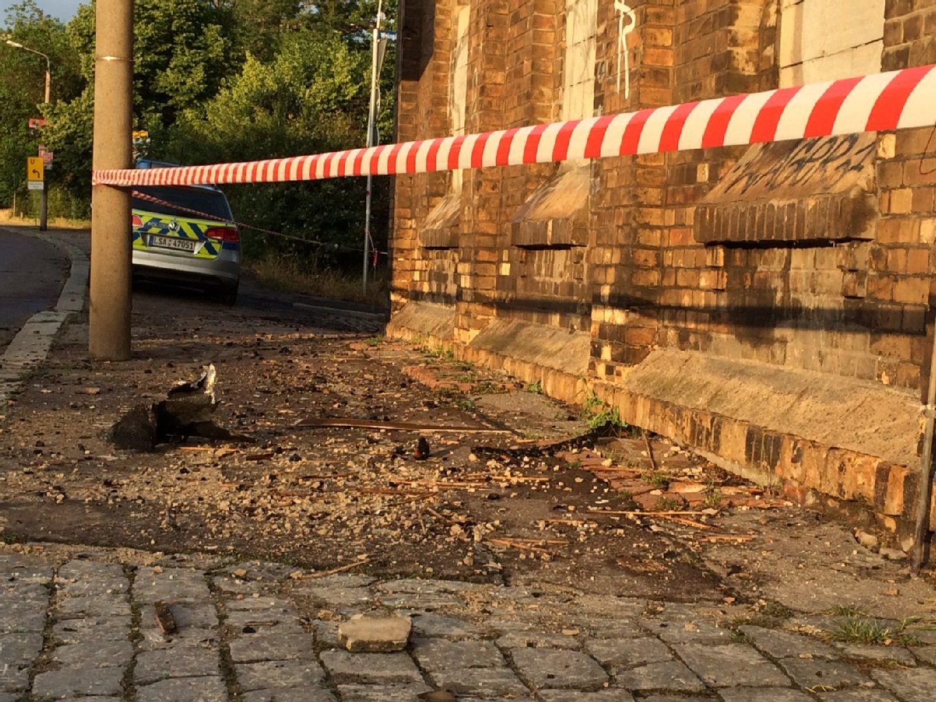 Putz und verkohlte Dachpappe liegen nach dem Brand auf dem alten Brauereigelände auf dem Fußweg.