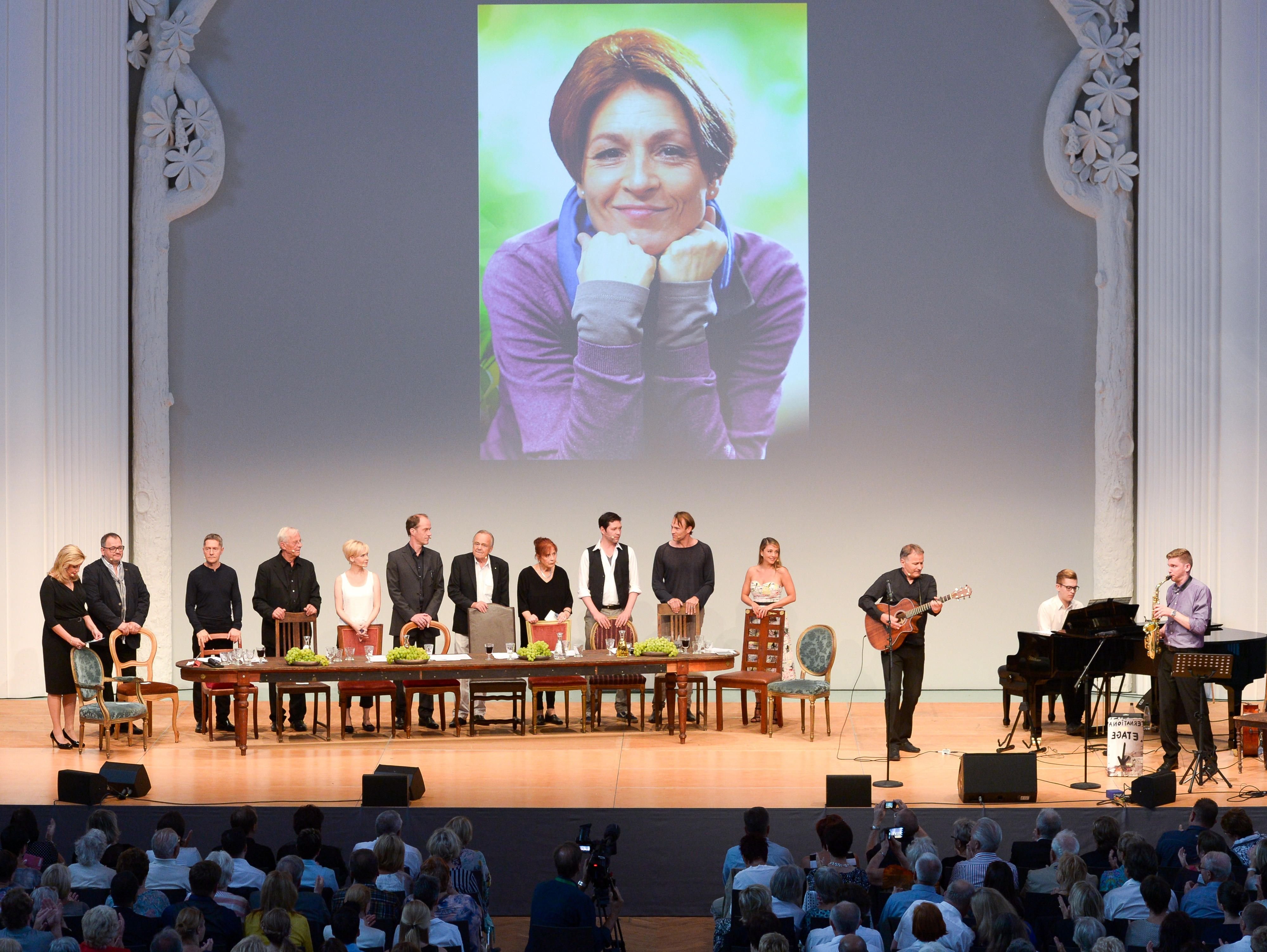 Unter dem Bild der verstorbenen Schauspielerin Hendrikje Fitz singt und spielt Schauspielkollege Thomas Rühmann (3.v.r.) ein Lied.