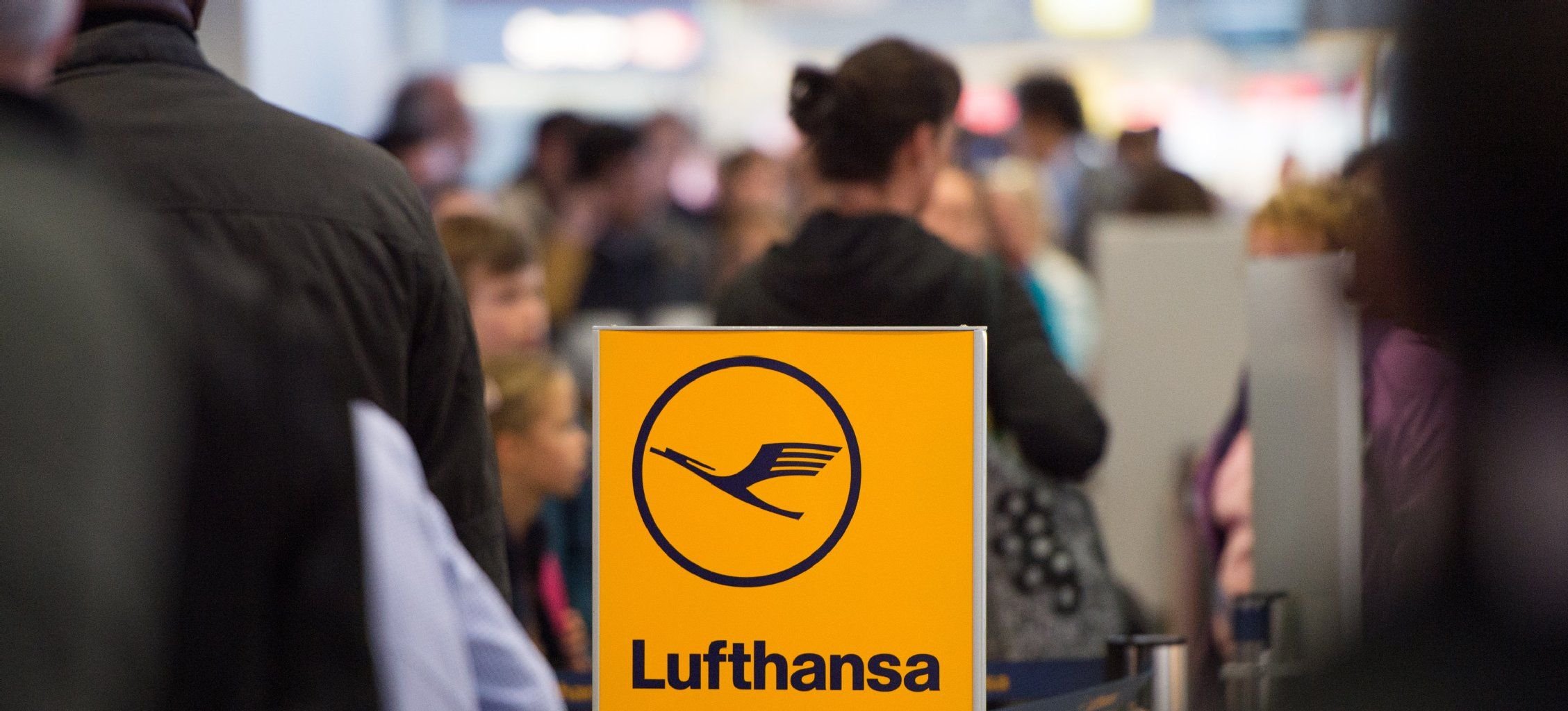Reisende der Fluggesellschaft Lufthansa warten an einem Check-In-Schalter.