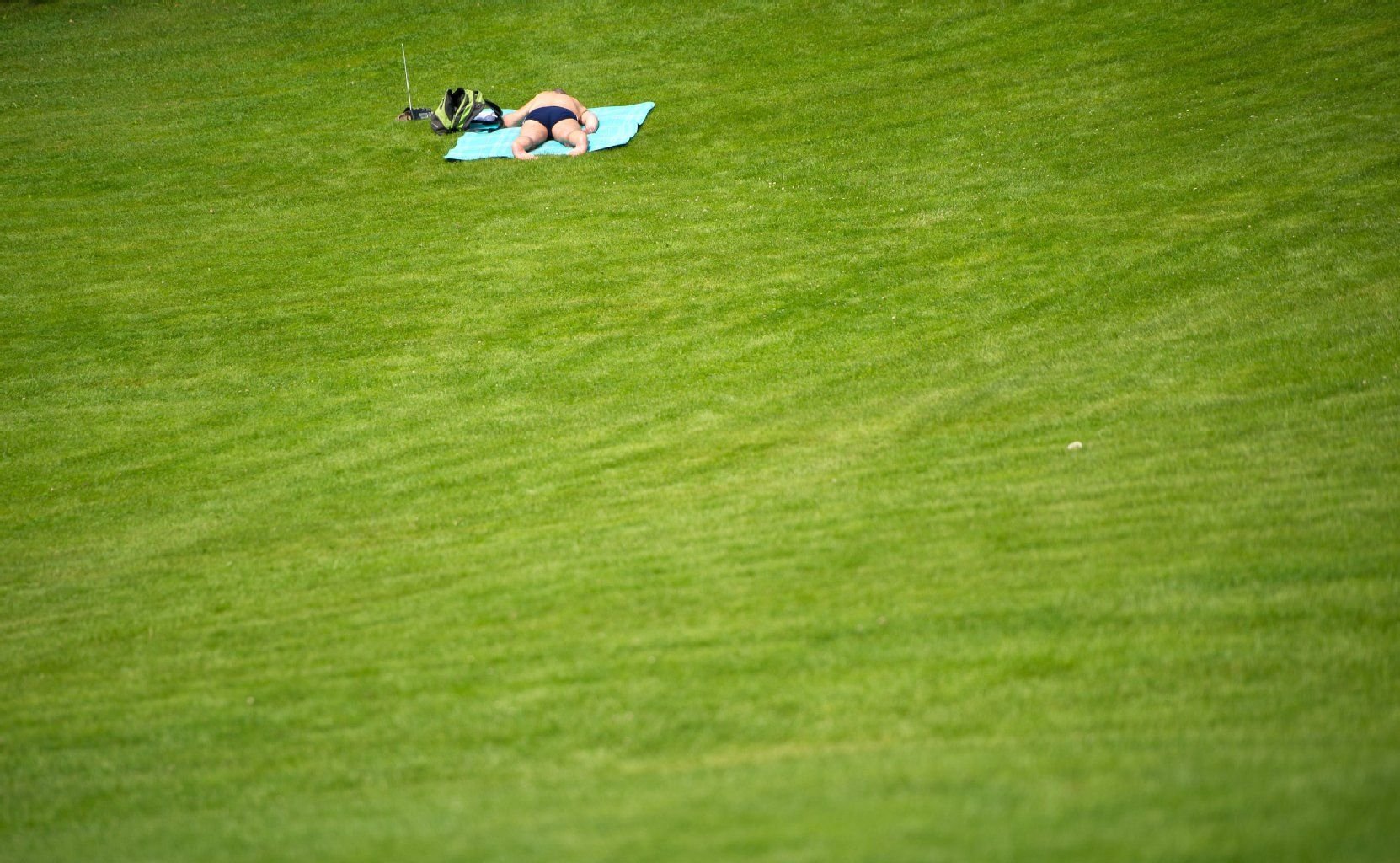 Ein Mann liegt auf einer Wiese in der Sonne.