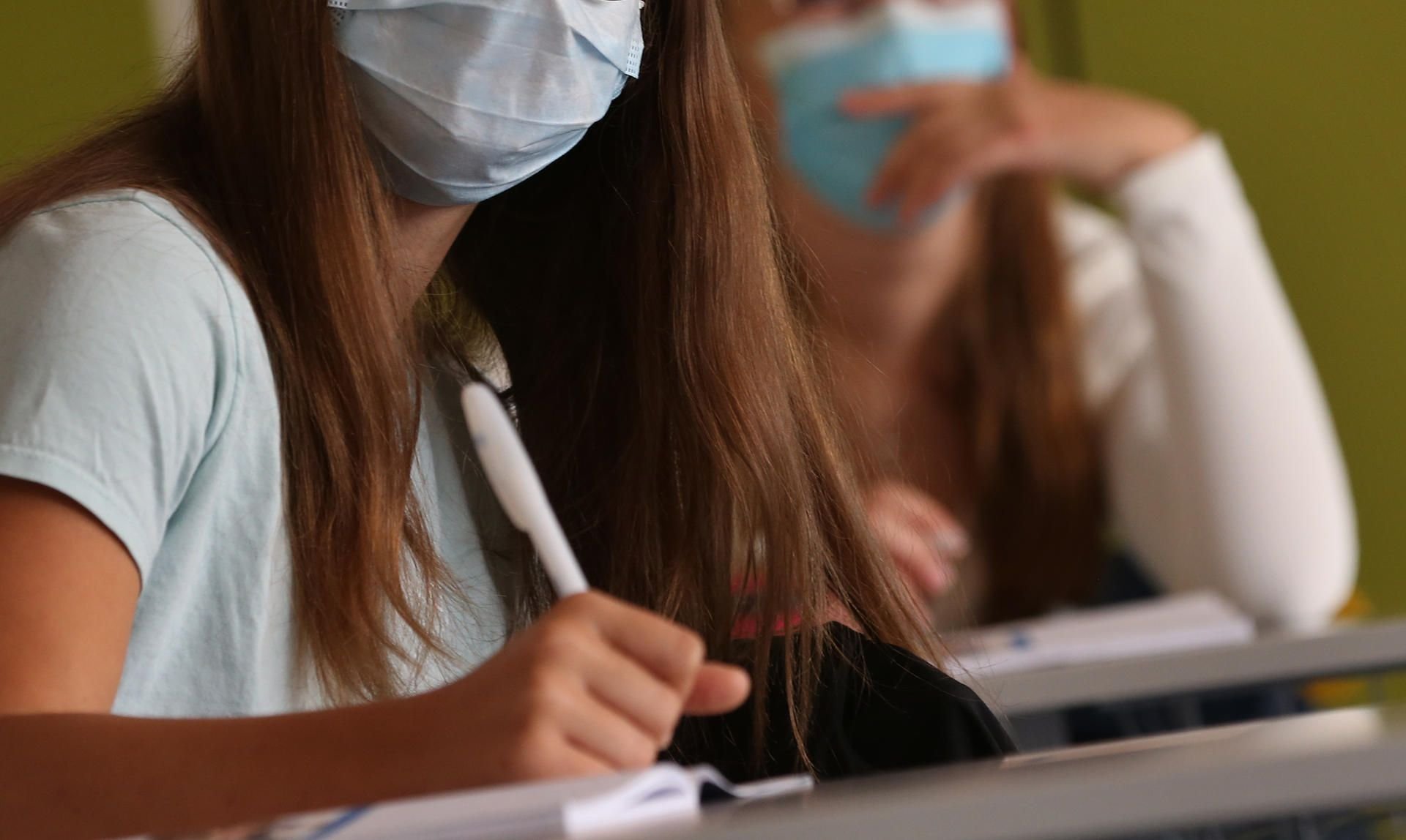 Schülerinnen sitzen zu Beginn des Unterrichts mit Mundschutz im Klassenzimmer.