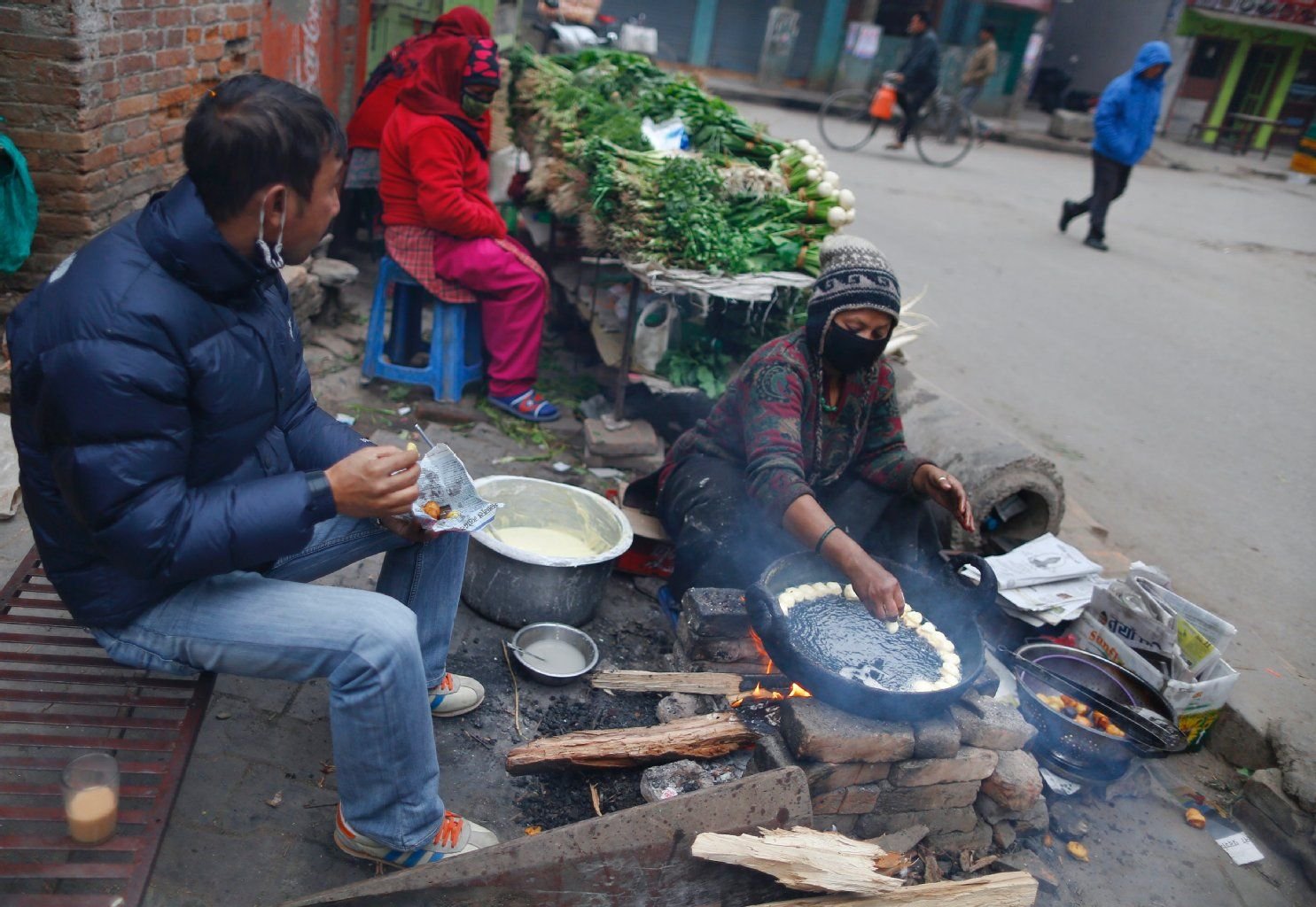 Eine Frau kocht am Straßenrand in Kathmandu Fulaura, ein traditionelles Frühstücksgericht.
