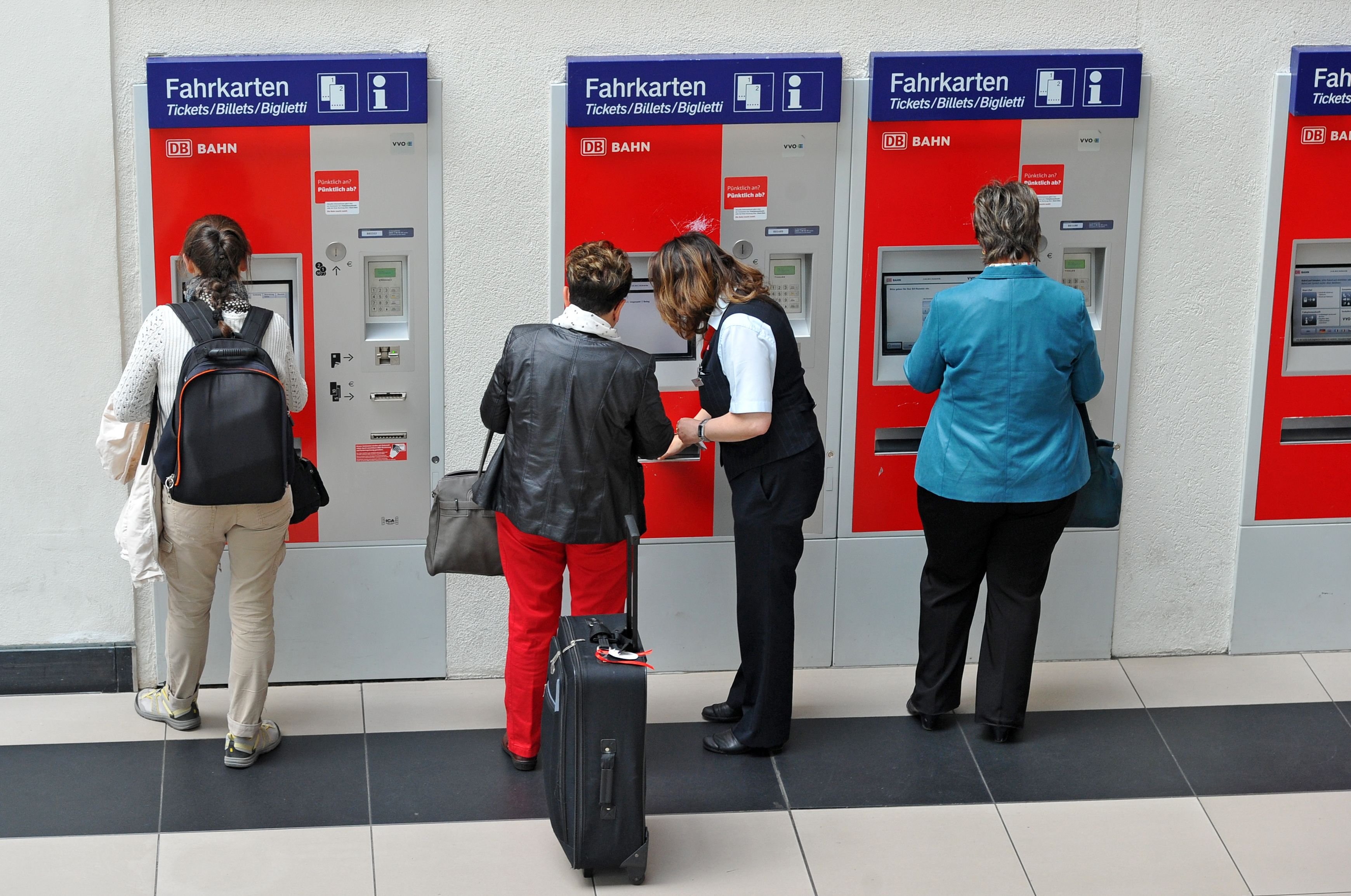 Menschen stehen im Bahnhof an Fahrkartenautomaten der Bahn.