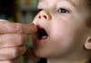Ein kleiner Junge bekommt kleine Kügelchen, so genannte Globuli, mit einer homöopathischen Arznei verabreicht.