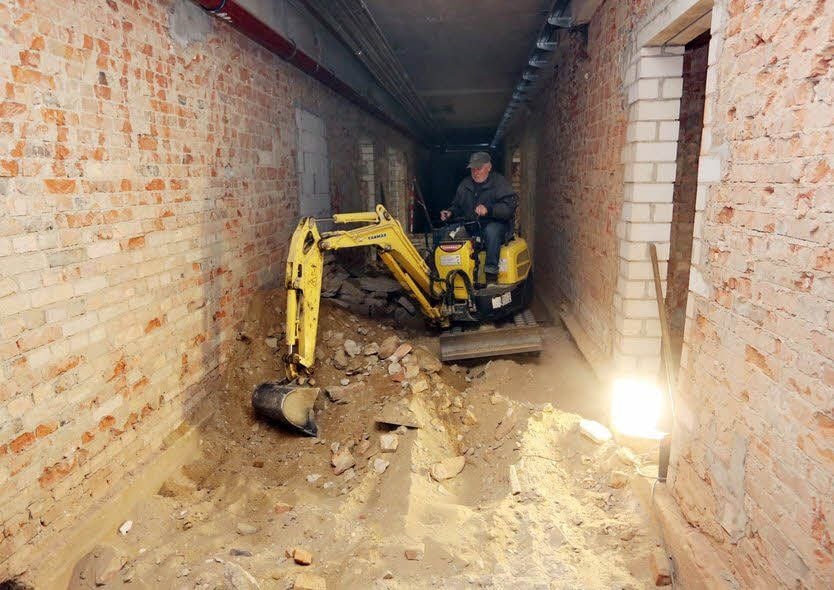 Heinz Stregge arbeitet mit einem Minibagger im Keller der Gebäudes.